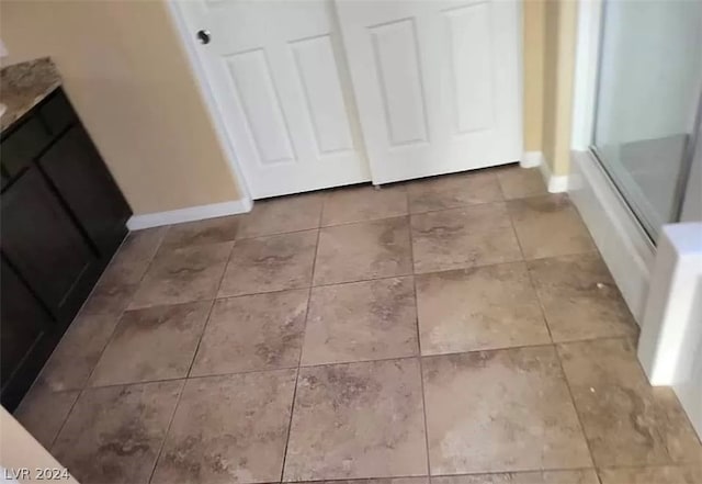 details featuring shower / bath combination with glass door, vanity, and light tile floors