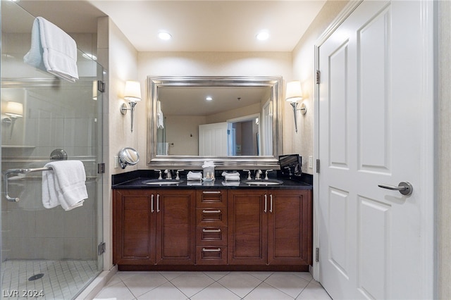 bathroom featuring a shower with shower door, double sink vanity, and tile floors