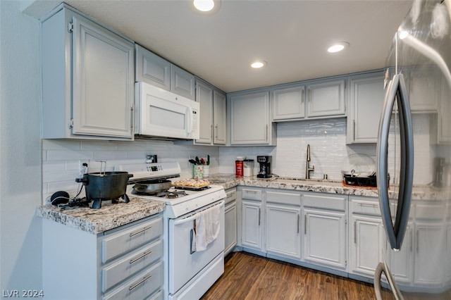 kitchen with sink, white appliances, backsplash, and dark wood-type flooring