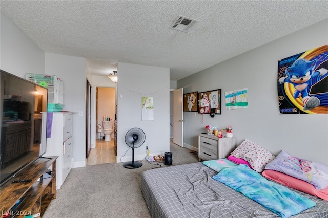 bedroom with connected bathroom, light carpet, and a textured ceiling