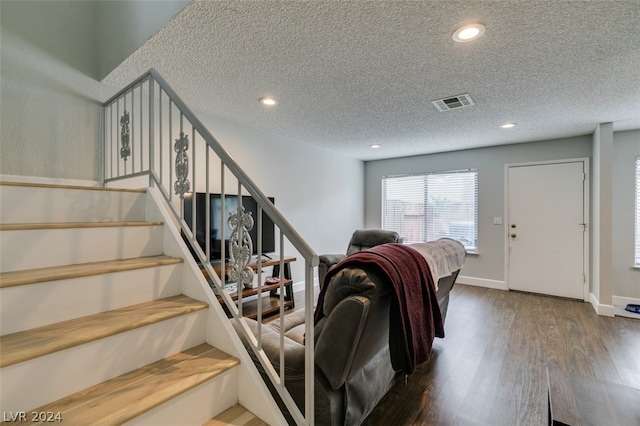 stairs featuring a textured ceiling and dark wood-type flooring