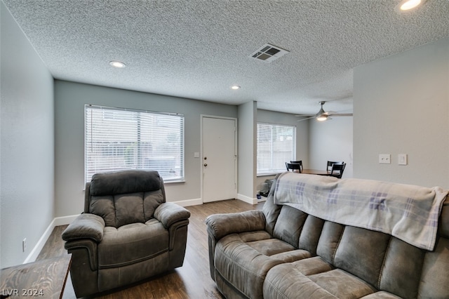 living room featuring dark hardwood / wood-style floors, ceiling fan, and a textured ceiling