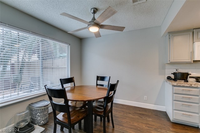 dining space with a textured ceiling, ceiling fan, and dark wood-type flooring