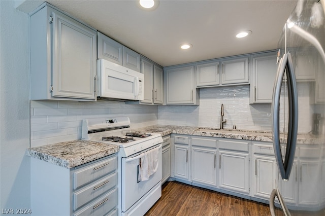 kitchen with white appliances, tasteful backsplash, dark hardwood / wood-style floors, and light stone countertops