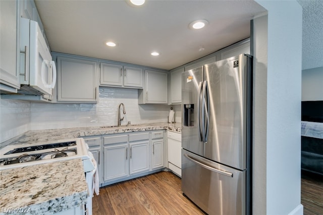 kitchen with light hardwood / wood-style flooring, white appliances, tasteful backsplash, light stone counters, and sink