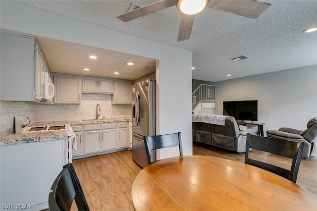 dining area featuring a textured ceiling, sink, ceiling fan, and light wood-type flooring