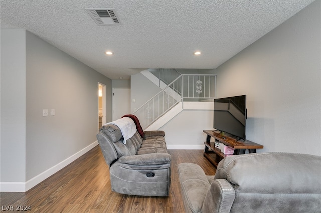 living room featuring dark wood-type flooring and a textured ceiling