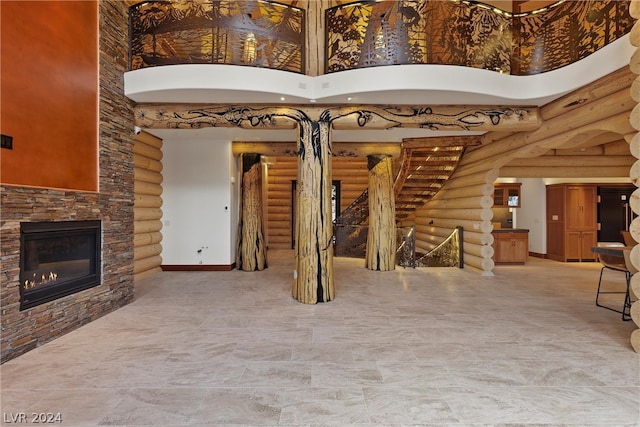 interior space with log walls, a high ceiling, and a stone fireplace