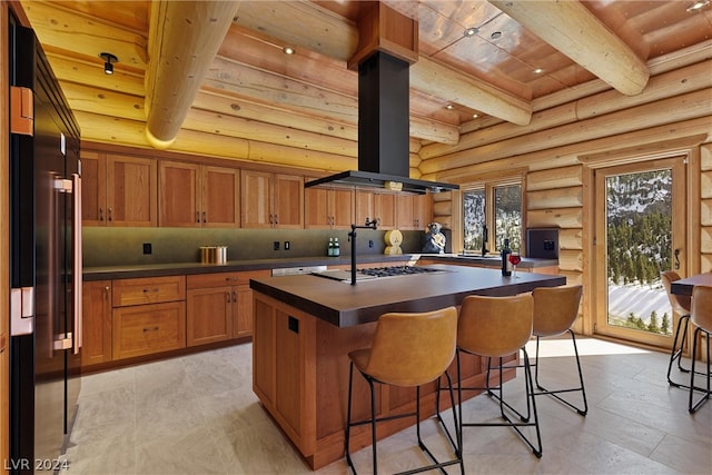 kitchen featuring wooden ceiling, a breakfast bar area, an island with sink, island exhaust hood, and rustic walls