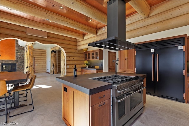 kitchen featuring rustic walls, beamed ceiling, island range hood, a stone fireplace, and high quality appliances