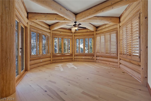 spare room featuring beam ceiling, rustic walls, ceiling fan, and light wood-type flooring