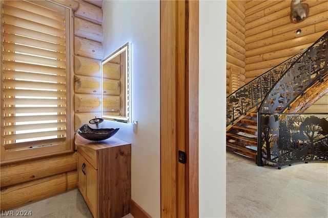 hallway with light tile flooring, rustic walls, and sink