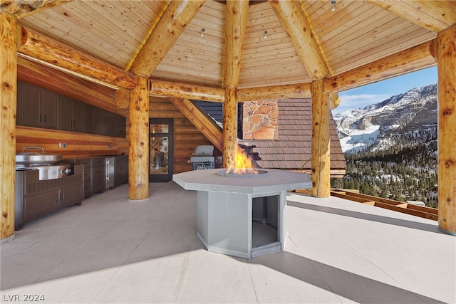 snow covered patio with exterior kitchen, grilling area, and a mountain view