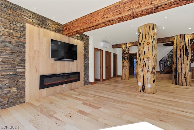 unfurnished living room featuring beamed ceiling and light hardwood / wood-style floors