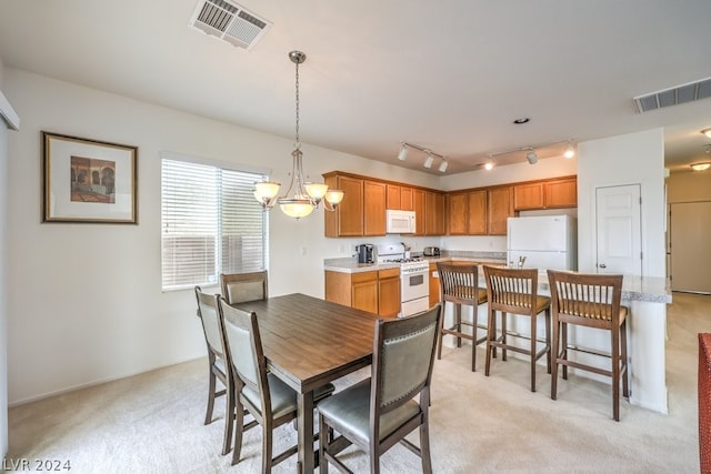 carpeted dining area with track lighting and a notable chandelier