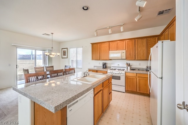 kitchen featuring white appliances, a chandelier, rail lighting, and a kitchen island with sink