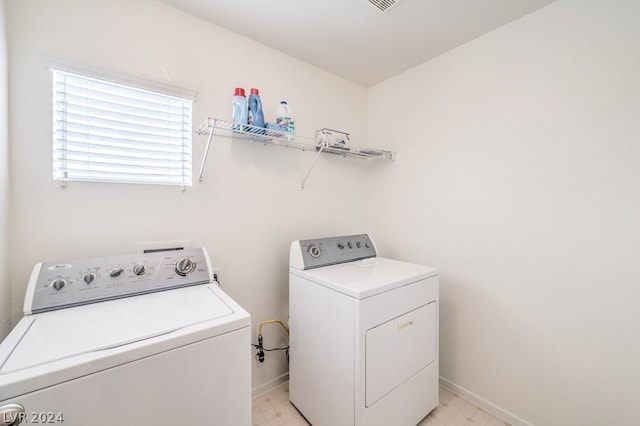 clothes washing area featuring washing machine and clothes dryer and light tile flooring