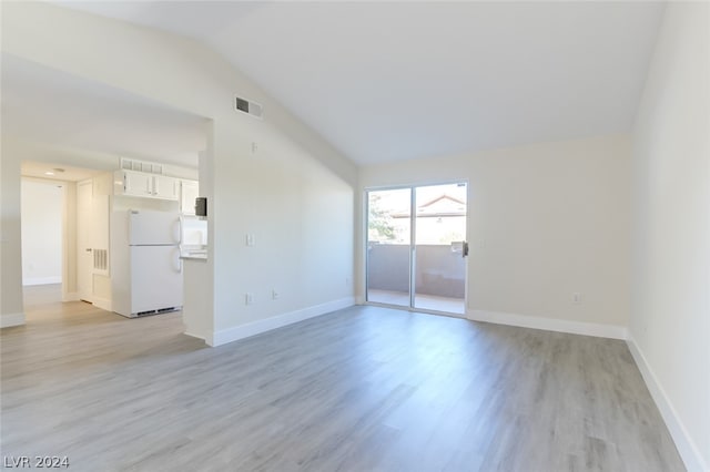 empty room featuring light wood-type flooring and vaulted ceiling