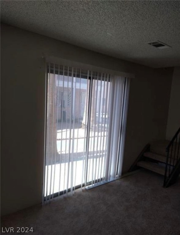 carpeted spare room with a textured ceiling