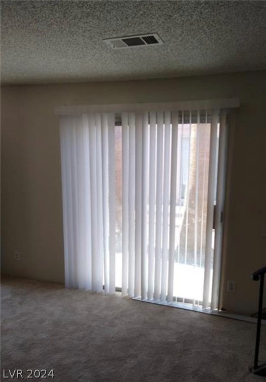 spare room featuring a textured ceiling and carpet floors