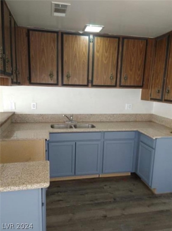 kitchen featuring sink, light stone counters, dark brown cabinetry, and dark hardwood / wood-style flooring