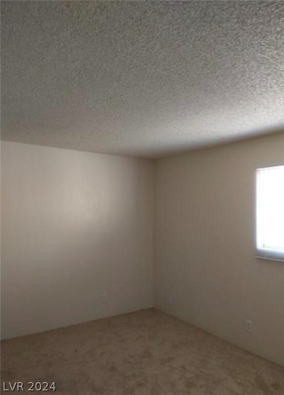 carpeted empty room featuring a textured ceiling