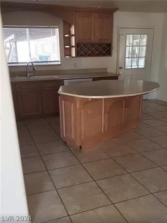 kitchen featuring sink, plenty of natural light, light tile floors, and a kitchen island