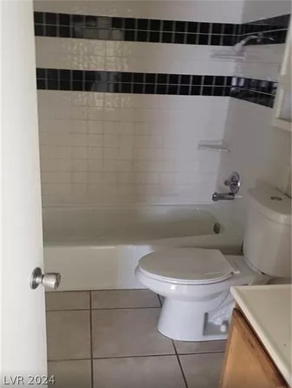 full bathroom with tiled shower / bath, vanity, toilet, and tile floors