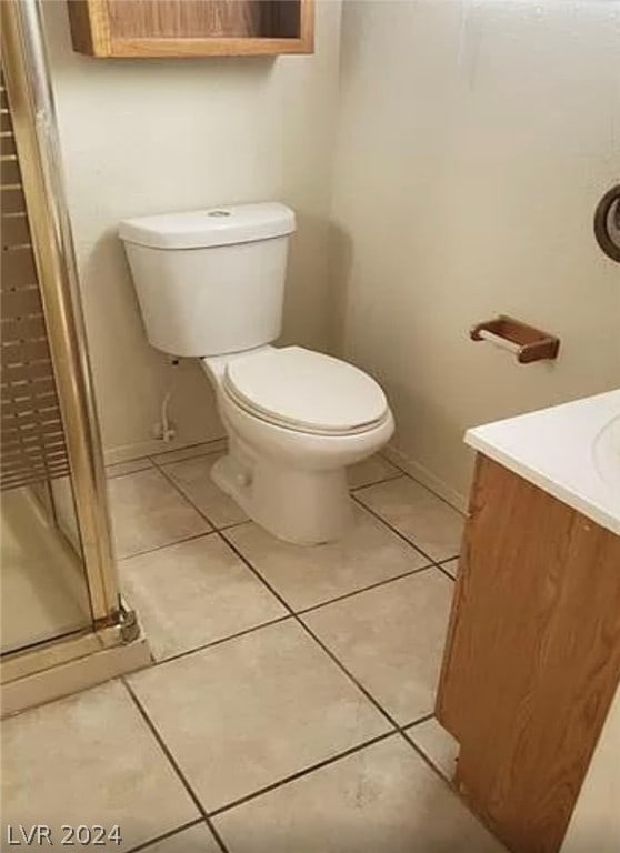 bathroom with a shower with door, tile flooring, vanity, and toilet