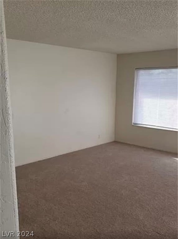 carpeted spare room featuring a textured ceiling