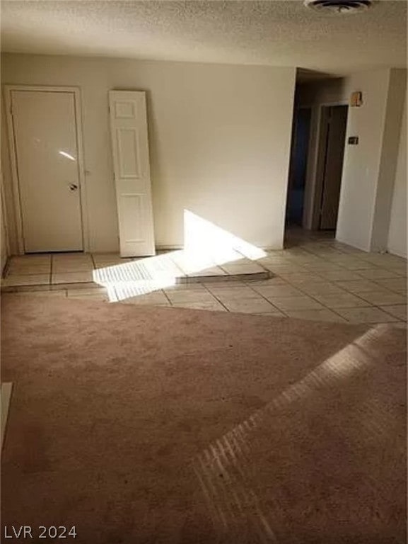 unfurnished room featuring a textured ceiling and light tile floors