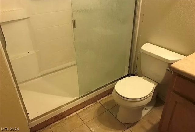 bathroom with toilet, tile floors, a shower with shower door, and vanity