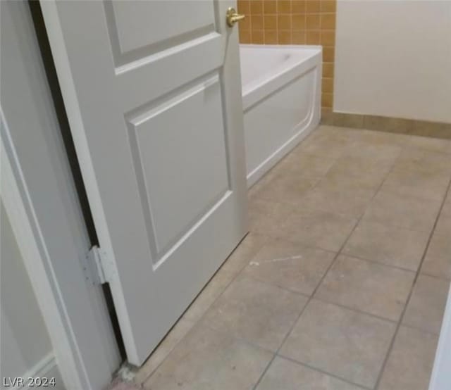 interior details featuring a washtub and light tile floors