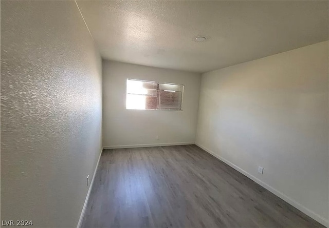 empty room with a textured ceiling and wood-type flooring