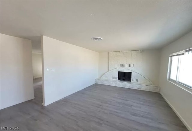 unfurnished living room featuring a brick fireplace, brick wall, and dark hardwood / wood-style floors