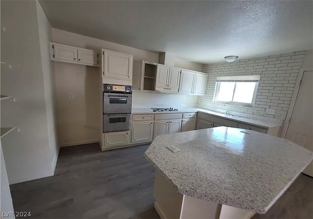 kitchen with white cabinetry, a textured ceiling, dark hardwood / wood-style flooring, and stainless steel appliances