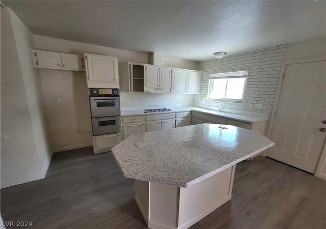 kitchen featuring dark hardwood / wood-style flooring, appliances with stainless steel finishes, a kitchen island, and white cabinetry