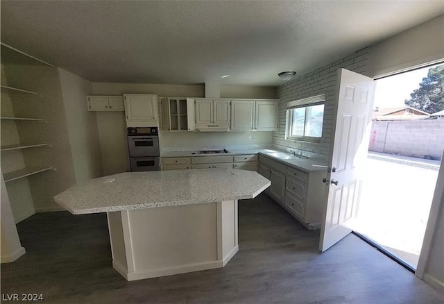 kitchen with a kitchen island, stainless steel appliances, sink, light stone countertops, and white cabinets