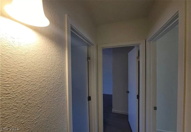 hallway featuring dark colored carpet