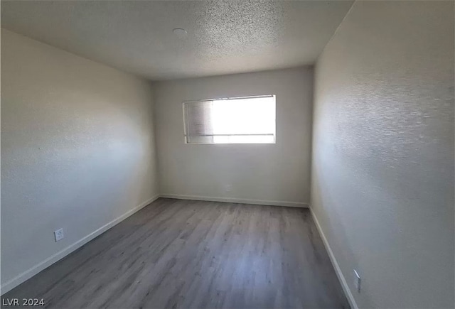 unfurnished room with a textured ceiling and light wood-type flooring