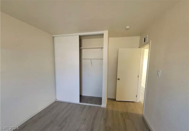 unfurnished bedroom with light hardwood / wood-style flooring and a closet