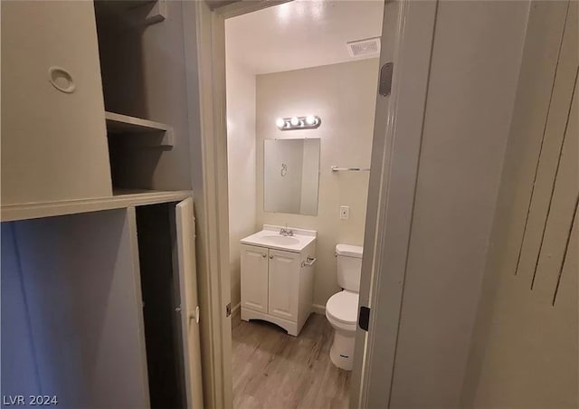 bathroom with hardwood / wood-style flooring, toilet, and vanity