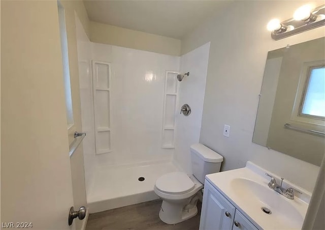 bathroom featuring a shower, toilet, wood-type flooring, and vanity