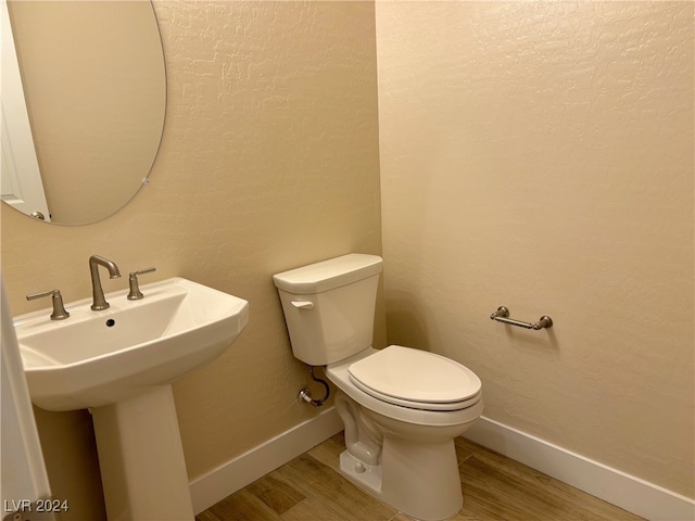 bathroom with toilet, wood-type flooring, and sink