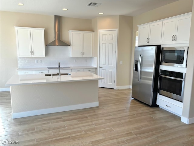 kitchen featuring white cabinets, backsplash, a kitchen island with sink, wall chimney exhaust hood, and stainless steel appliances