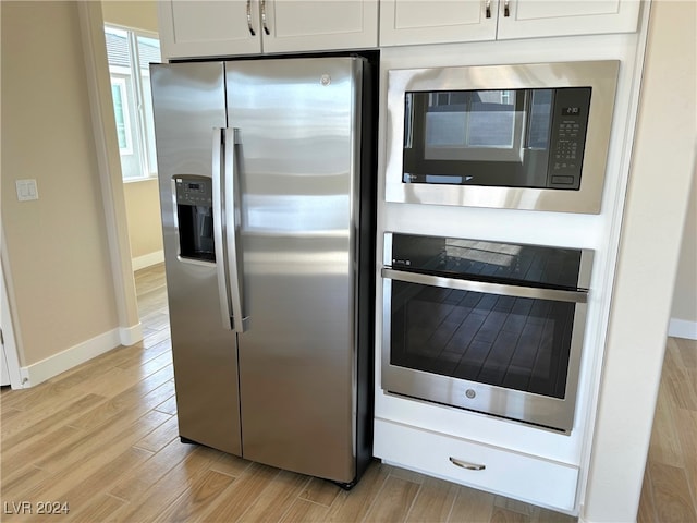 kitchen with stainless steel appliances, light hardwood / wood-style flooring, and white cabinets