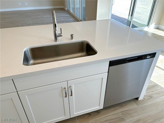 kitchen featuring dishwasher, light hardwood / wood-style flooring, sink, light stone countertops, and white cabinets