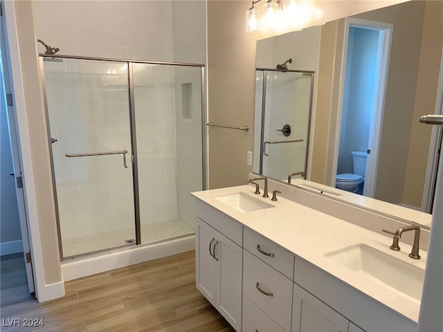 bathroom featuring toilet, hardwood / wood-style floors, vanity, and a shower with door