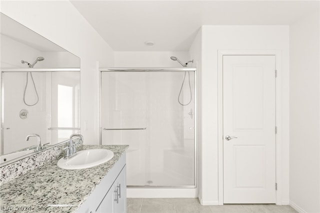 bathroom featuring tile flooring, large vanity, and a shower with door