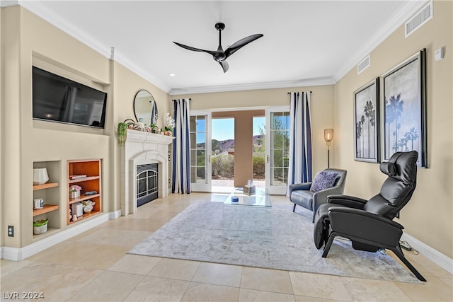 living area featuring ceiling fan, crown molding, built in shelves, and light tile flooring